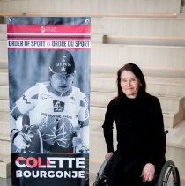 Colette Bourgonje posing by Order of Sport banner