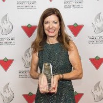Inductee Colleen Jones holding her induction award on the red carpet