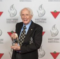 Inductee Dr. Frank Hayden holding his induction award on the red carpet