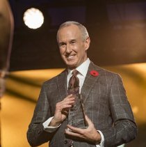 MC Ron MacLean holding an induction award onstage