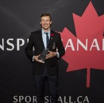 Inductee Simon Whitfield holding his induction award on the red carpet