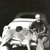 Bob Adams with deer and holding rifle