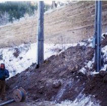 Workman standing next to a large spool of electrical wire