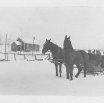 Horses pulling a sleigh with five people in cutter