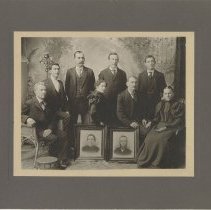 Photograph of eight people with two framed portraits