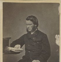 Man sitting by a table reading a book - Front