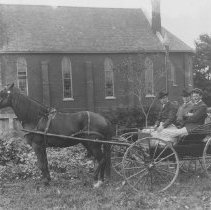 K-81-13-31 Three men in a carriage parked by a church.