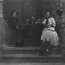 K-81-13-33 Two women seated at table on front porch.