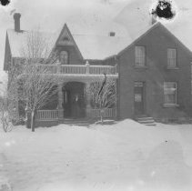 K-81-13-09 Large home in town, with man standing on front porch.