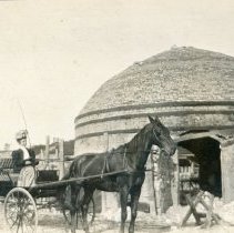 Woman in horse drawn buggy outside brick kiln