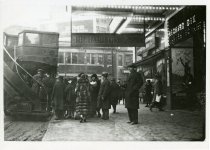 Black and white glossy photo shows people disembarking a double decker bus in front of the Madison Theatre