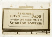 Black and white photographic print depicting a Walker & Co. billboard displaying an advertisement for Father and Son Weeks