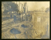 Sepia-toned photo showing two recently-constructed brick manholes