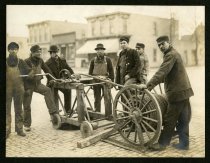 Sepia-toned photo showing construction workers who are operating a manual winch over an open manhole