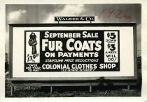 Black and white photographic print depicting a Walker & Co. billboard displaying an advertisement for Colonial Clothes Shop