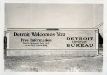 Black and white photographic print depicting a Walker & Co. billboard displaying an advertisement by the Detroit Convention & Tourist Bureau