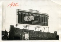 Black and white photographic print depicting a Walker & Co. billboard displaying an advertisement by the Detroit Creamery
