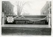 Black and white photographic print depicting a Walker & Co. billboard displaying an advertisement for the Detroit Trust Company