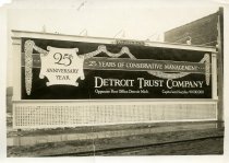 Black and white photographic print depicting a Walker & Co. billboard displaying an advertisement for the Detroit Trust Company