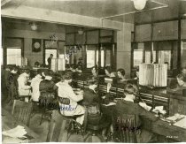 Halftone black and white print of a photograph depicting the interior of the offices of the Merchants Credit Bureau, located within the Merchants Building on the east corner of Grand River Avenue and Broadway Avenue