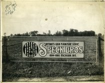Black and white photographic print on fabric backing depicting a sign advertising Speck Bros