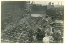 Digital scan of a sepia-toned photo overlooking the construction site for the Detroit terminal of the Detroit-Windsor Tunnel, as taken from a point above its west side, above Bates Street, facing northeast