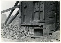 Digital scan of a sepia-toned photo taken of the underpinning put in place beneath the south wall of a brick building at 232 Randolph Street during the construction of the Detroit-Windsor Tunnel