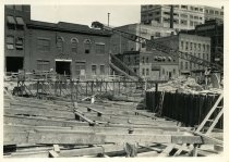 Digital scan of a sepia-toned photo overlooking the bracing along the cut excavated for the approach to the Detroit-Windsor Tunnel in the northeast corner of the construction site for the Detroit terminal, taken facing the northeast toward the foot of Fra