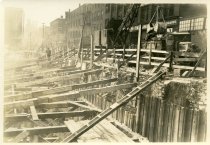 Digital scan of a sepia-toned photo taken looking across the excavation along Woodbridge Street dug during the construction of the Detroit-Windsor Tunnel, as taken facing northwest