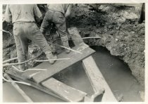Digital scan of a sepia-toned photo of a close-up of construction beneath Randolph Street for the Detroit-Windsor Tunnel