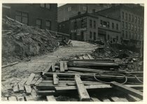 Digital scan of a sepia-toned photo of the wooden ramp leading from the intersection of Randolph Street and Franklin Street into the excavation for the Detroit-Windsor Tunnel on the construction site for its Detroit terminal