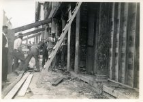Digital scan of a sepia-toned photo of workers underpinning the Darmstaetter property at the northeast corner of Randolph Street and Atwater Street as viewed from beside the building facing north along Randolph
