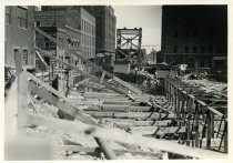 Digital scan of a sepia-toned photo taken overlooking the bracings for the excavation dug along Randolph Street during the construction of the Detroit-Windsor Tunnel, as taken from Woodbridge Street, facing south
