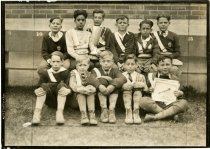 Sepia-toned group portrait photograph children belonging to the Flint Auto Club Patrollers posed sitting along and in front of a row of benches