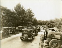 Mounted sepia-toned photograph of a road crowded with early automobiles at Phoenix Park, near 5 Mile Road and Northville Road
