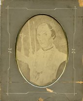 Sepia-toned photograph of an engraving of Father Gabriel Richard in a gray cardboard frame with gold metallic oval surrounding the image