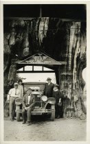 Black and white photograph of five individuals, consisting of three men and two women, standing and sitting near a Packard Motor Car Co