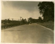 Black and white photographic print of two Packard automobiles driving on a rural road