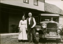 Black and white photographic print of Gratia and John Wilder standing next to a Packard automobile in Plymouth Notch, VT
