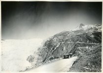 Black and white photographic print showing a Packard 8 convertible parked along a mountain road in the Swiss Alps