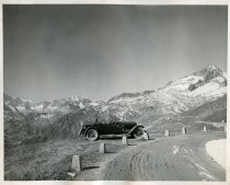 Black and white photographic print of a right side profile view of a Packard 8 convertible parked along the side of a mountain road in the Swiss Alps