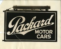 Black and white photographic print depicting a sign that reads Packard Motor Cars