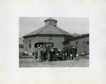 Black and white photographic print taken outside depicting a Packard four door sedan from the front, passenger side