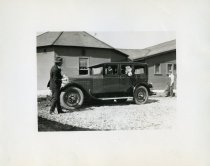 Black and white photographic print taken outside depicting a Packard four door sedan from the driver side