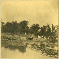 Mounted sepia-toned photo of park goers crossing the wooden bridge over the lily pond on Belle Isle