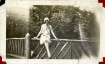 Sepia-toned photo of Edna Summers posed seated on the wooden railing of one of the bridges over Belle Isle's canal system