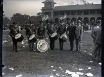 Monochromatic glass-plate negative (and black and white print) of a drum corps composed of uniformed Spanish-American War veterans from Wichita, Kansas posed on the lawn in front of the Belle Isle Casino during the National Convention of the United Spanis