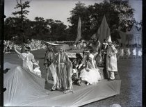 Monochromatic glass-plate negative taken costumed performers on a parade float during the Blue Bird Pageant on Belle Isle
