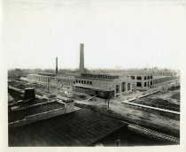 Black and white print shows an arial view of the construction of the Packard Plant in Detroit