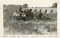 Black and white photo of a woman in a dark gown, a man in a bow tie and jodhpurs, and a man in a boater hat and suit posed beside an early automobile with a coupe body in Marblehead, Ohio
